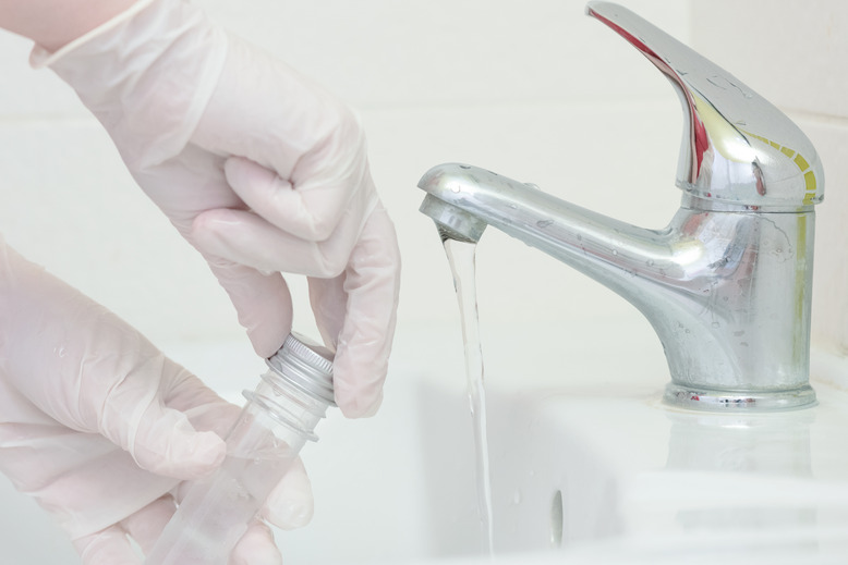 Water technician drawing tap water for testing