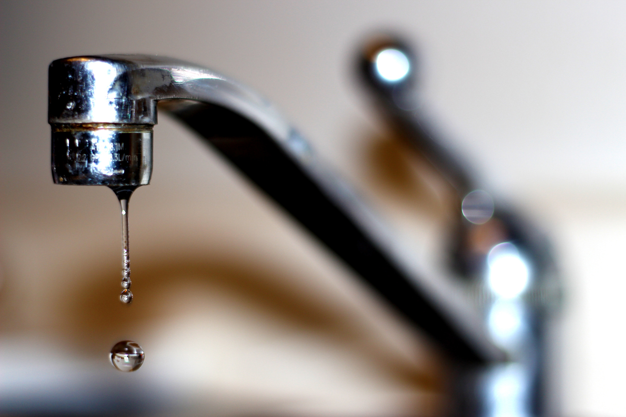 A faucet dripping hard water.